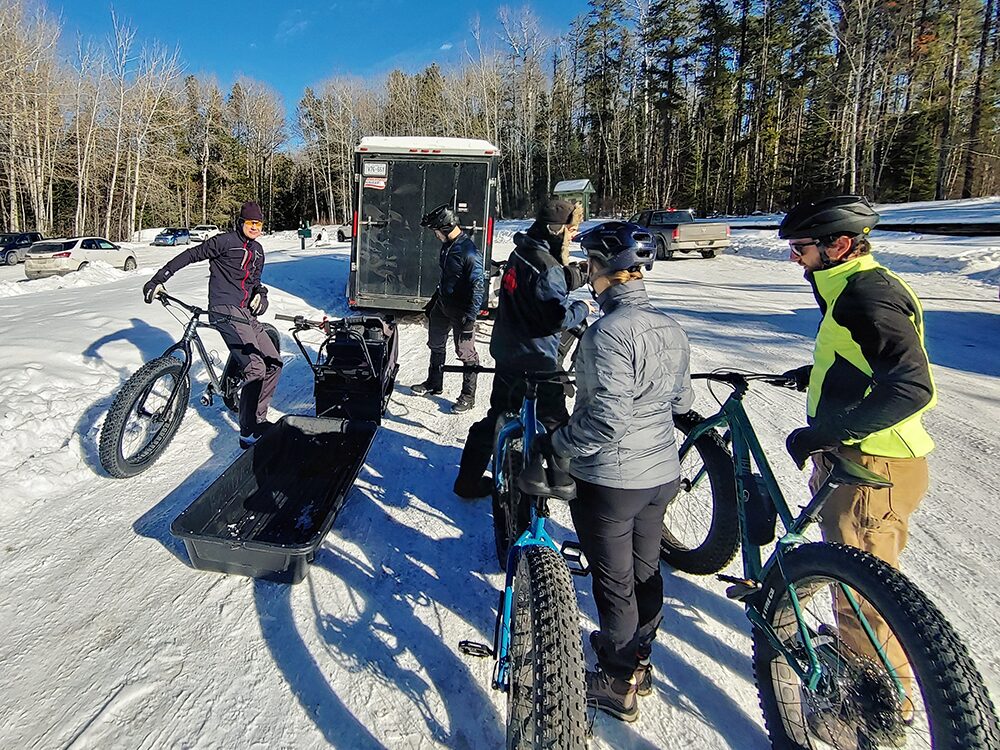 Cyclists getting ready to ride fat bikes in the snow.